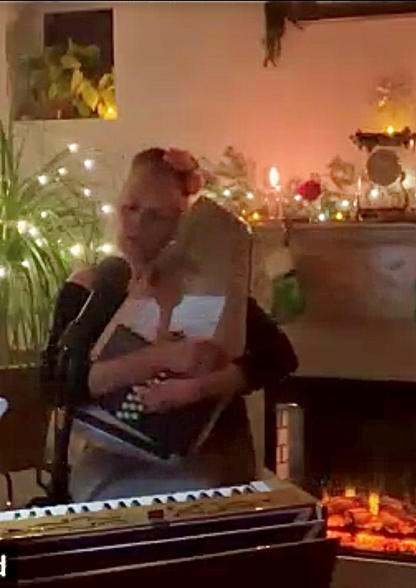 Photo of Sawyer singing in front of a cozy fire